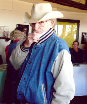 Veteran screen badman George Keymas slinks for the camera at a 2006 Roy Rogers festival in Victorville, CA. Longtime stuntman for James Garner, Roydon Clark is seated in the background.