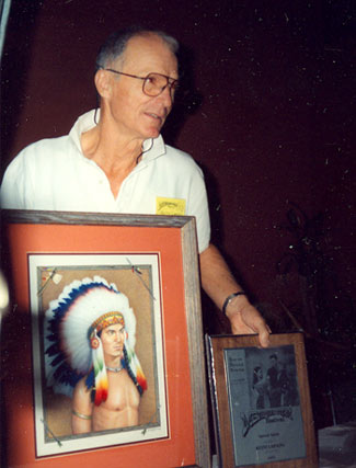 Keith Larsen holds up a painting of himself as TV’s “Brave Eagle” and his award at the Memphis, TN, Film Festival in 1992.