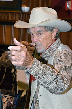 Buck Taylor takes aim with an imaginary rifle.