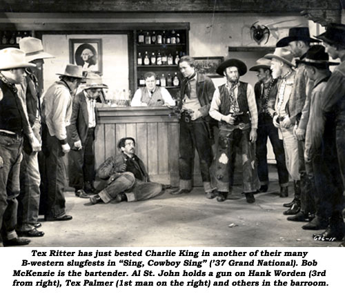 "Tex Ritter has just bested Charlie King in another of their many B-western slugfests in "Sing, Cowboy, Sing" ('37 Grand National). Bob McKenzie is the bartender. Al St. John holds a gun on Hank Worden (3rd from right), Tex Palmer (1st man on the right) and others in the barroom."