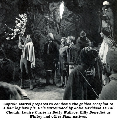 Captain Marvel prepares to condemn the golden scorpion to a flaming lava pit. He's surrounded by John Davidson as Tal Chotali, Louise Currie as Betty Wallace, Billy Benedict as Whitey and other Siam natives.