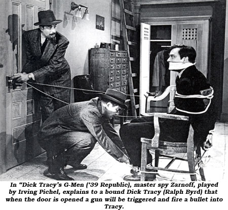 In "Dick Tracy's G-Men" ('39 Republic), master spy Zarnoff, played by Irving Pichel, explains to a bound Dick Tracy (Ralph Byrd) that when the door is opened a gun will be triggered and fire a bullet into Tracy.
