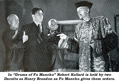 In "Drums of Fu Manchu" Robert Kellard is held by two Dacoits as Henry Brandon as Fu Manchu gives them orders.