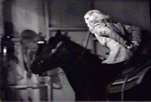 Dorothy, with hands tied behind her back, rides toward window.