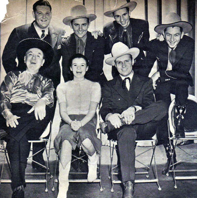 Gene Autry and his “Melody Ranch” radio show gang: (L-R top) announcer Tom Hanlon, The Rough Riders Trio (Jimmy Wakely, Johnny Bond, Dick Reinhart). (L-R seated) Shorty Long as portrayed by Horace Murphy, Mary Lee and Gene Autry. 
