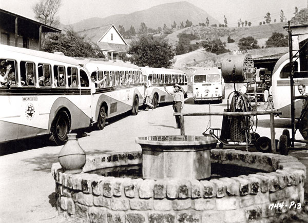 While filming “Ride Clear of Diablo”, Audie Murphy waves at the Universal-International tourist buses on the U-I backlot. 