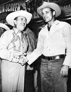Warner Bros. honcho Jack Warner congratulates Guy Madison on the success of “Charge at Feather River” and now the release of “The Command”. 