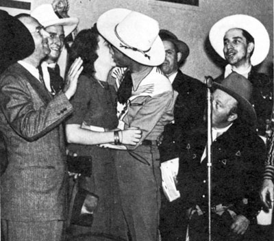 Roy gives a hug and a kiss to Mrs. M. E. Goodman in Baltimore after she bought a $100 war bond. Her husband is on the left. 