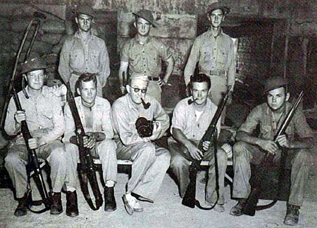 Director John Ford (center) poses with Marines and members of his crew while carefully cradling one of his arms. While Ford was filming the Japanese attack on Midway on June 4, 1942 a bomb blast riddled his shoulder with shrapnel and knocked him unconscious. He later noted, “I did manage to get the picture.” 