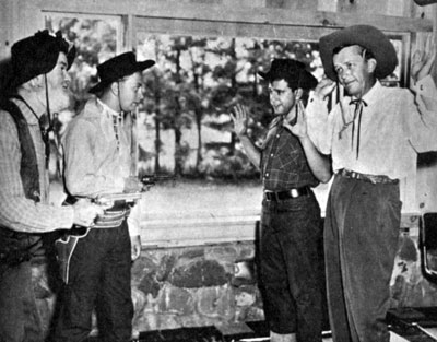 Gag shot as Gabby Hayes and Mel ?? hold guns on Mel’s pals Dick Hayes and Bobby Sherwood. 