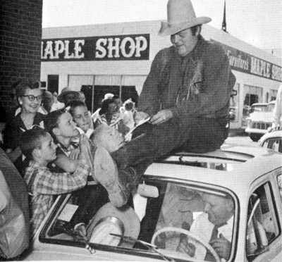 Dan “Hoss” Blocker signs autographs in front of a maple syrup shop.