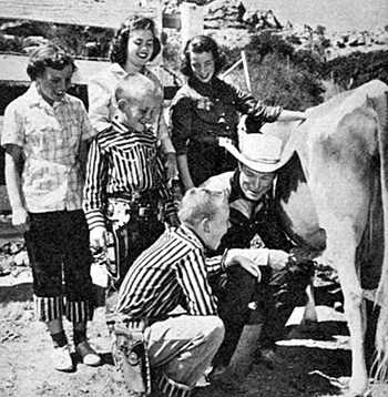 Roy teaches his children the art of miling a cow.