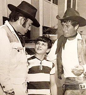 James Drury “The Virginian” and Robert Fuller of “Laramie” greet a young fan in between filming. 