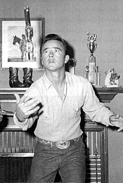 Dick Jones demonstrates the art of gun spinning in his living room. Note the framed still of Dick and his horse from “Rocky Mountain” hanging over the fireplace and the boots on the mantel. The picture was from his favorite film and the boots are the ones he wore in “Trail of the Hawk” (‘35). (Thanx to Ann Snuggs.) 