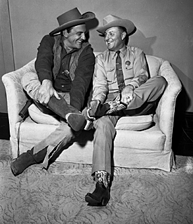 “Gunsmoke”’s James Arness compares boot sizes with Texas Ranger Captain Clint Peoples while Arness was in Tuscon, AZ on January 30, 1959. Peoples extended an invitation to attend a dinner in Austin, TX where Arness would be made an honorary Ranger. 