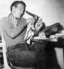 Preparing for another Republic Western, Rex Allen polishes up his six-gun.