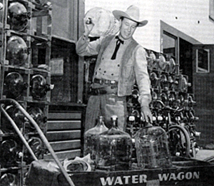 Publicity photo of Bill Elliott loading bottles on to the Republic Studio Water Wagon.