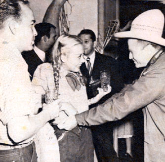 Don Barry clowns around with a pig-tailed Adele Mara as he attempts to pull the rope holding up Adele’s blue jeans.