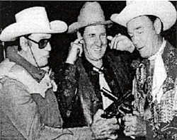 Pat Buttram holds his ears as Clayton "Lone Ranger" Moore and 
Roy Rogers compare guns. 