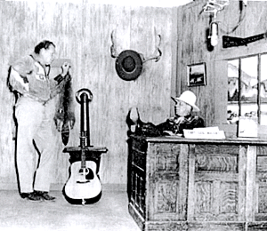 Hoot Gibson is sitting at the desk during a break on Ozie Waters' KBTV TV show out of Denver, CO, circa 1954. Note the microphone on the upper right. Ozie had a Junior Ranger Club with 40,000 kids who were members. 