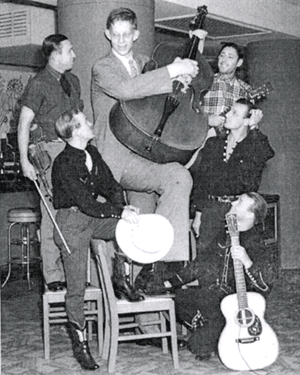 The Sons of the Pioneers look up to the Giant of Illinois, Robert Pershing Wadlow, who was 8'11" and 439 pounds. Roy Rogers kneeling on the right, Bob Nolan above him, Karl Farr above him. On the left Tim Spencer in dark shirt looking up, Hugh Farr with fiddle.. 