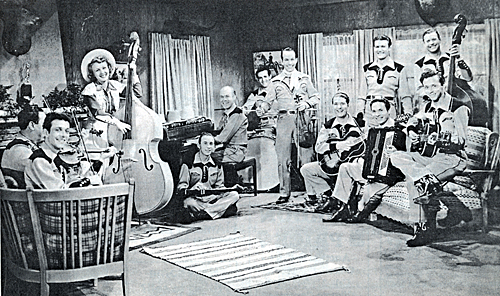 Jam session in a private home featured Spade Cooley (center with fiddle), Tex Williams standing to the left of Cooley. Seated on the couch in front of Tex is Leo "Pedro" DePaul. Carolina Cotton holds the bass fiddle. Several members of the group departed in 1946 to start Tex Williams' Western Caravan.