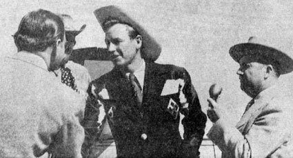 Rex Allen is greeted by Kansas Lt. Gov. Fred Hall at the airport. Partially obscured on the left is R. C. Hill, on the right is Herschel Holland, radio station KGNO program director who interviewed Rex.