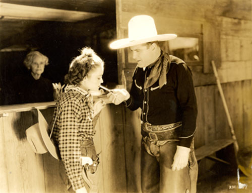 Ken Maynard lights up for leading lady Lona Andre between scenes of “Trailing Trouble” (‘37 Grand National).