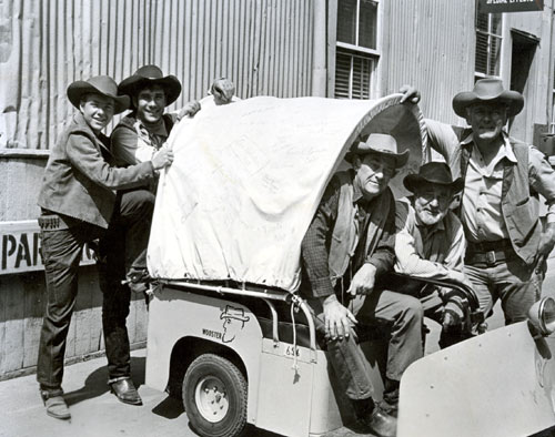 The later cast of “Wagon Train” gather around Frank McGrath’s Wooster-Wagon on the Universal back lot. (L-R) Michael Burns, Robert Fuller, John McIntire, Frank McGrath (as Charlie Wooster) and Terry Wilson. You probably can’t read them in this photo but the wagon tarp is covered with autographs.