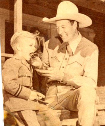 Bill Elliott takes time to feed a bite of cake to a young boy (at some sort of military school judging by the uniform?) in 1941.