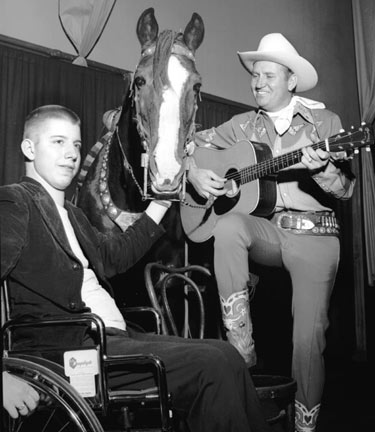 In a wheelchair, sixteen year old Ben Jarrett of Lexington, TN, visits Gene Autry during his appearance in Memphis, TN, on November 23, 1952. Gene first met Jarrett two years prior when the boy was flat on his back paralyzed from the waist down after he was injured diving into a shallow stream. (Thanx to Ray Nielsen.)