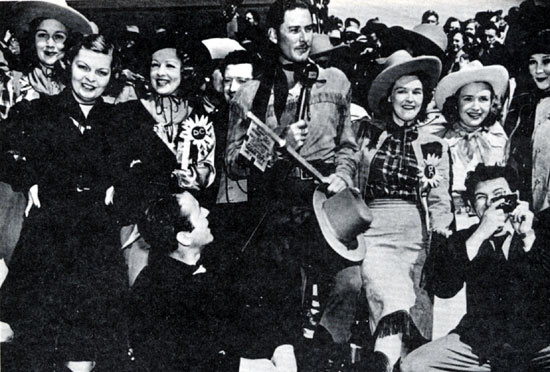 (L-R) Lola Lane (with hat), Mayo Methot, Humphrey Bogart (sitting), Claire Windsor, Frank McHugh (behind Flynn), Rosemary and Priscilla Lane, John Garfield (with camera) and Jean Parker join Errol Flynn in accepting the key to the city of Dodge City, Kansas during the November 1938 premiere of Warner Bros.’ “Dodge City”.