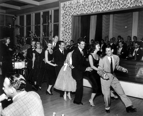 Ray Anthony leads a group as they dance to his big hit of “The Bunny Hop” at Ciro’s. Behind Anthony is actress Mitzi Gaynor and Hugh O’Brian. Man with the mustache is comedian Jerry Colonna. Marie Windsor watches on the left.