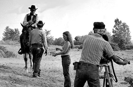 Cameraman Darrell Cathcart sets up for a scene with Sunset Carson in “Marshal of Windy Hollow”. Kathy Patton is holding the clapboard and Jerry Whittington walks toward Sunset.