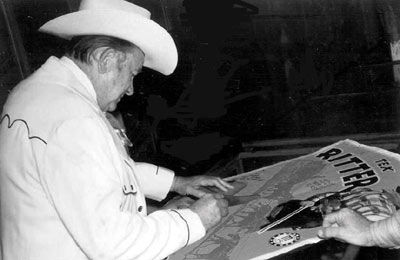 Tex Ritter signs one of his movie posters for a fan during the filming of “Marshal of Windy Hollow”.