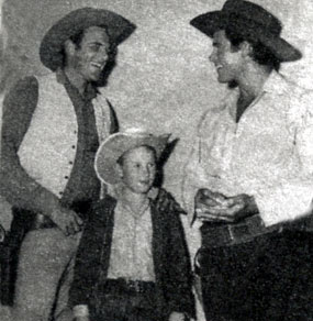 Two TV western giants and one small fry. James Arness of “Gunsmoke” chats with Clint Walker of “Cheyenne”.
