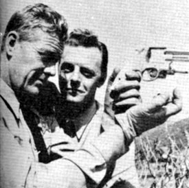 Examining a pistol in-between scenes of TV’s “Tales of the Texas Rangers” are stars Willard Parker (Jace Pearson) and Harry Lauter (Clay Morgan). Circa 1959.