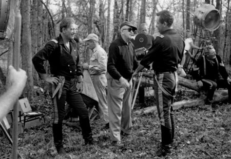 John Ford gives direction to John Wayne and William Holden before their big fight scene in “The Horse Soldiers”. Stuntman Fred Kennedy (seen here to the right playing a Cavalry sergeant) was killed in a horse-fall during the making of the film.