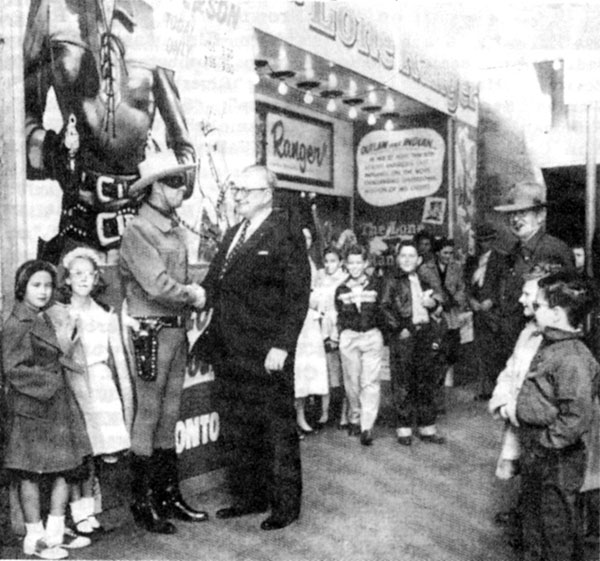 Clayton Moore is greeted by Ray Jones, manager of the Worth Theatre in Fort Worth, TX, along with a throng of admiring children during the 1956 promotional tour for the theatrical version of “The Lone Ranger”.