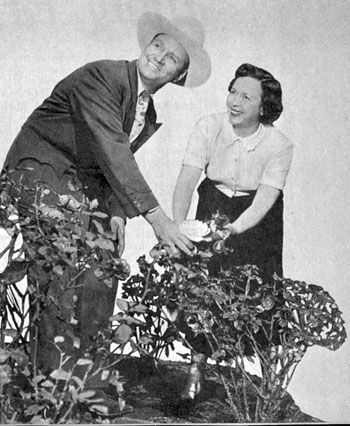 Gene Autry and his wife Ina examine a rose in the garden of their North Hollywood home in May, 1951.