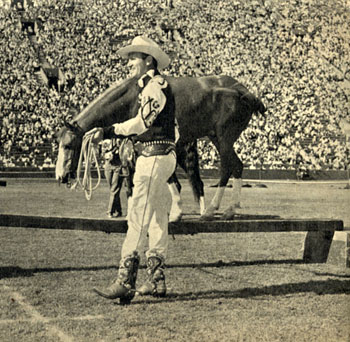 Gene Autry puts Little Champ (?) through his trick paces at the rodeo.