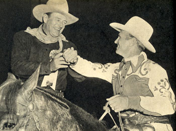John Wayne obliges Gene Autry who needed a little help with his cuff button.