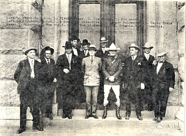 Tom Mix (front row third from right) stands in front of the north entrance to the Texas State Capitol with Texas Rangers (L-R back row) Flevis (illegible last name), man misidentified as Tim McCoy (unless that was the name of this Ranger), unknown Ranger. (L-R front row) illegible, Berger Moleswo???, Capt. Frank Hamer, unknown, Mix, Tom Hickman, L. E. Trimble, Sag Cummings.