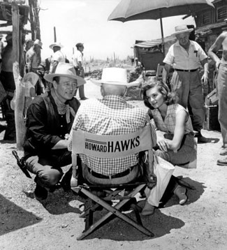 John Wayne and Angie Dickinson listen to director Howard Hawks on the set of “Rio Bravo” (‘59 Warner Bros.).