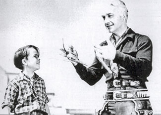 Willliam Boyd (Hopalong Cassidy) impresses young Dickie Jones with some fancy gun handling during the making of “The Frontiersman” (‘38 Paramount).