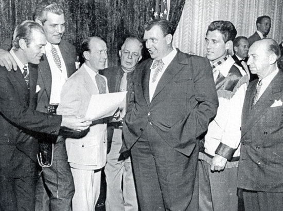 Reshearsing a song for a charity affair are Allan “Rocky” Lane (sans hairpiece), Buddy Baer, Tim Spencer, Hoot Gibson, Andy Devine, Ken Curtis and Roscoe Ates.