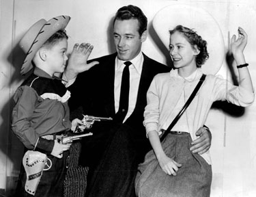 Sixguns in hand, five year old Dickie Barrett aims to get Wild Bill Hickok’s contribution to the Heart Fund while Guy Madison was filming “The Command” in 1954.