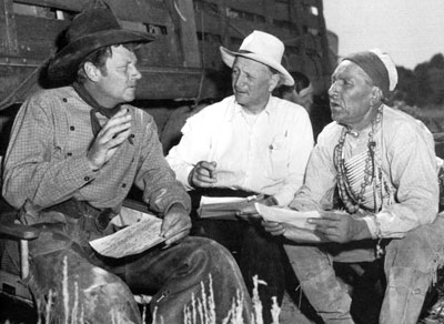On location for “The Outriders”, Joel McCrea goes over some script pages with script supervisor Don McDougal and Nipo T. Strongheart.