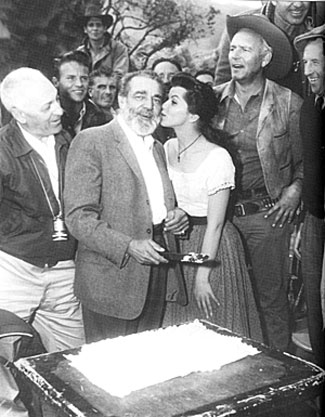 Frank McGrath, Charlie Wooster on “Wagon Train”, celebrates his 58th birthday on February 2, 1961 while filming the “Tiburcio Mendez Story” and receives a kiss from guest star Lisa Gaye. Terry Wilson in on the right. Cinematographer Walter Stenge is on the left.