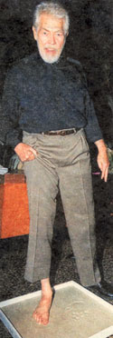 An elderly James Coburn leaves his footprint in cement at a Paris, France 
celebrity hangout. 